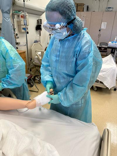 Nursing Exploration Project member wrapping an injured synthetic patient's foot.